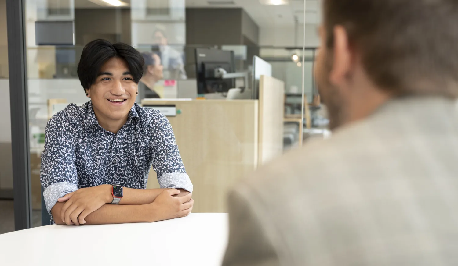 Student and adult sitting at table having a conversation.