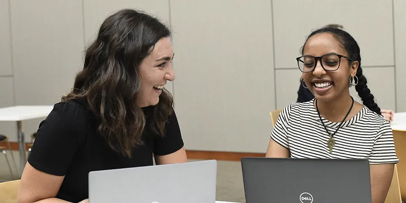 Two people at table with laptops 