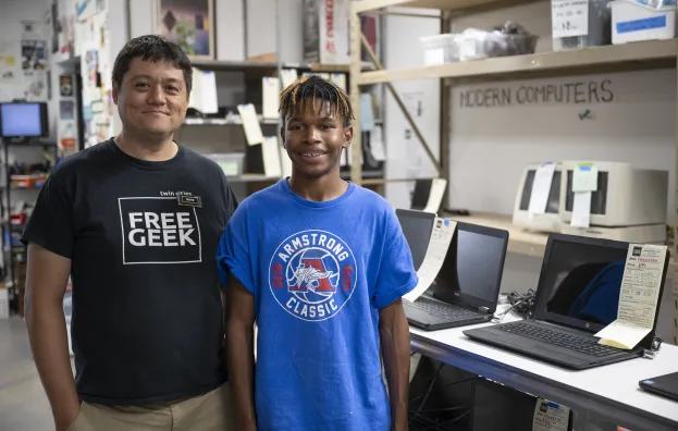 Free Geek supervisor and intern standing in tech workspace