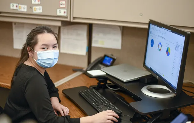 Woman wearing a mask working at a desktop computer