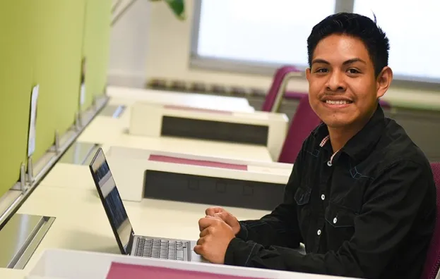 Young person working at a computer smiling at the camera