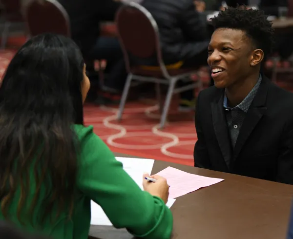 A woman talks with a student at a table 