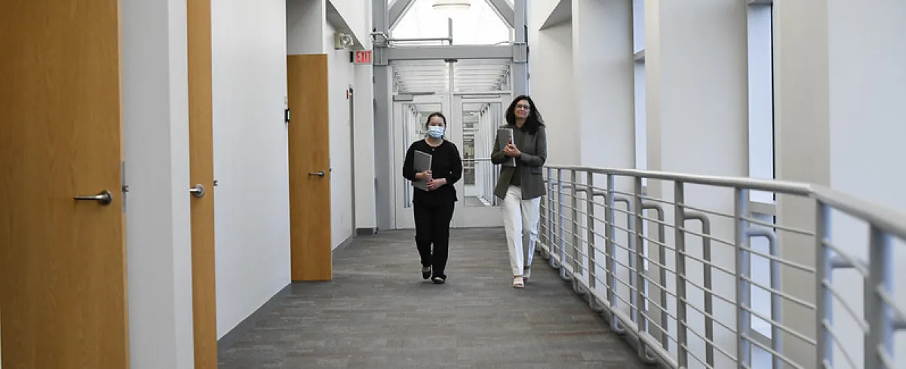 Two people walking down an office hallway