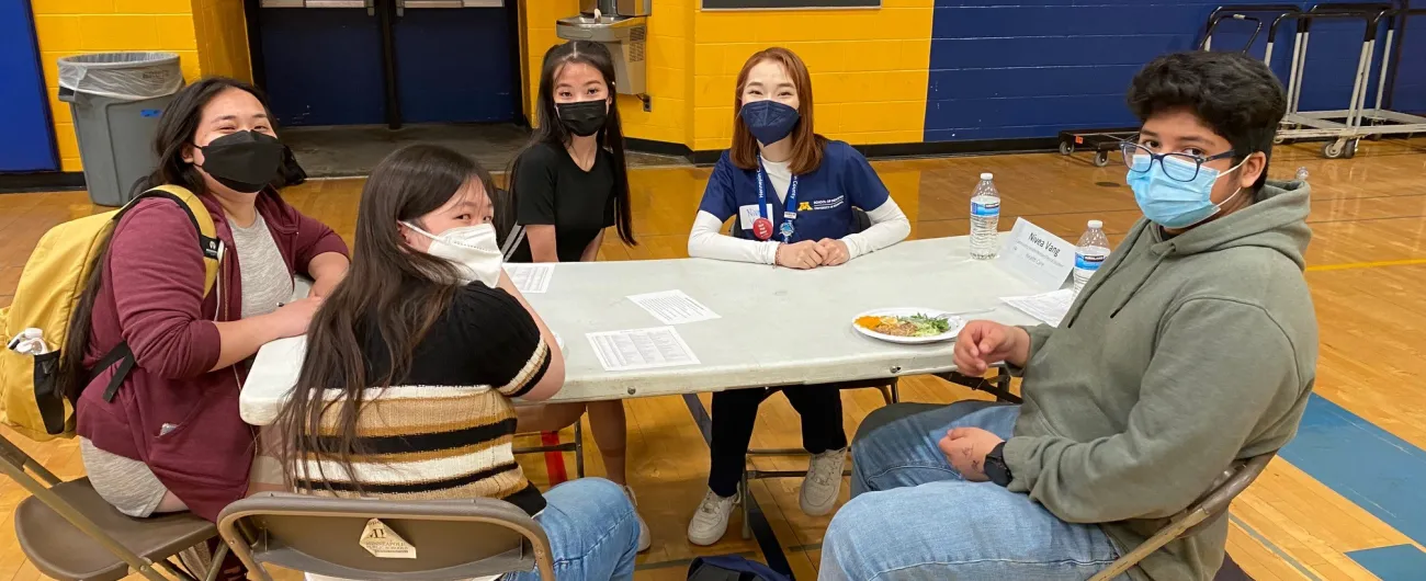 health worker talking with students in a school gym