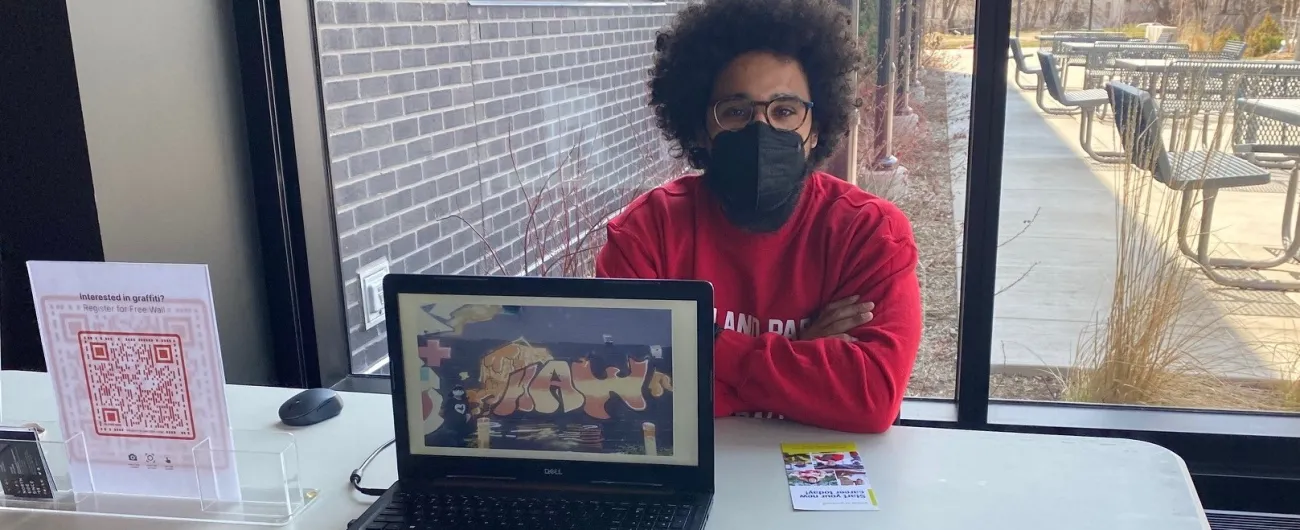 Man at display table with laptop, looking at the camera