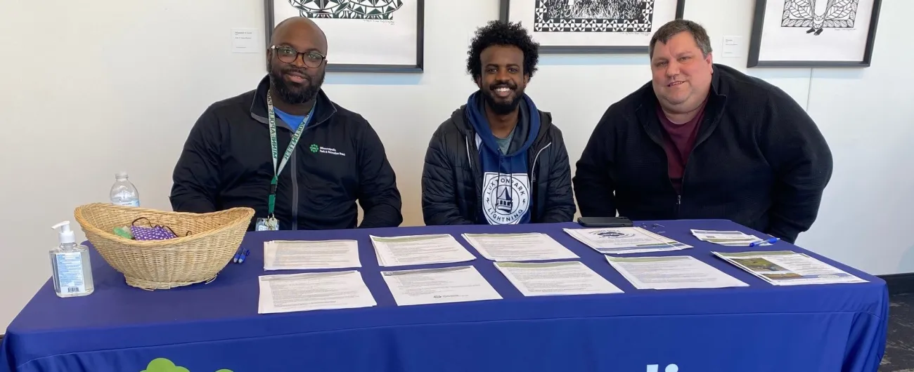 Three men sitting behind table for Minneapolis Parks and Rec