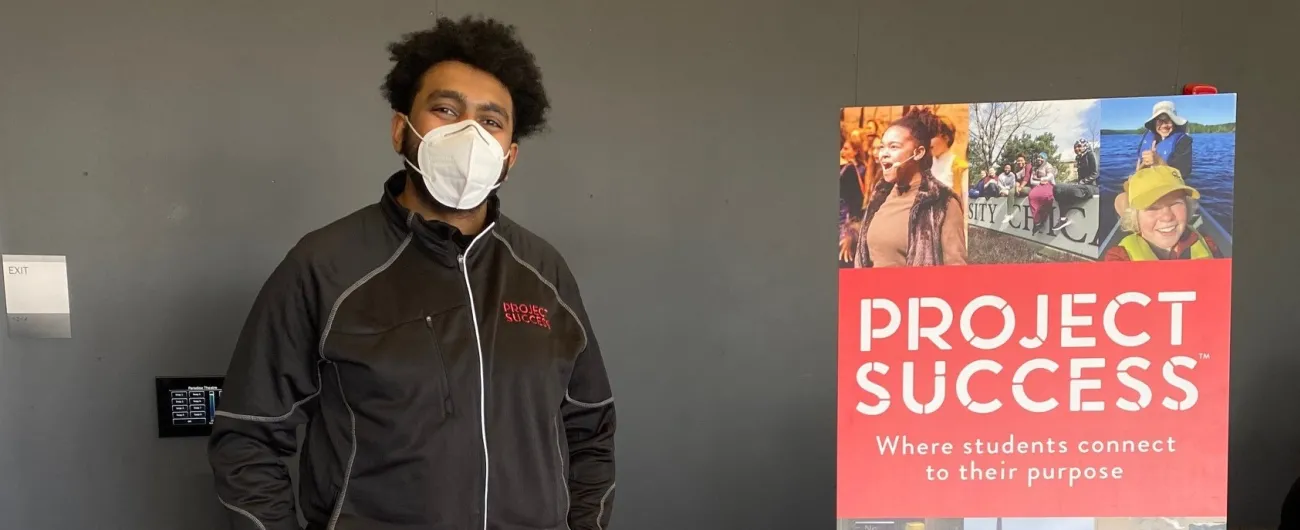 Man standing at table next to poster that says Project Success