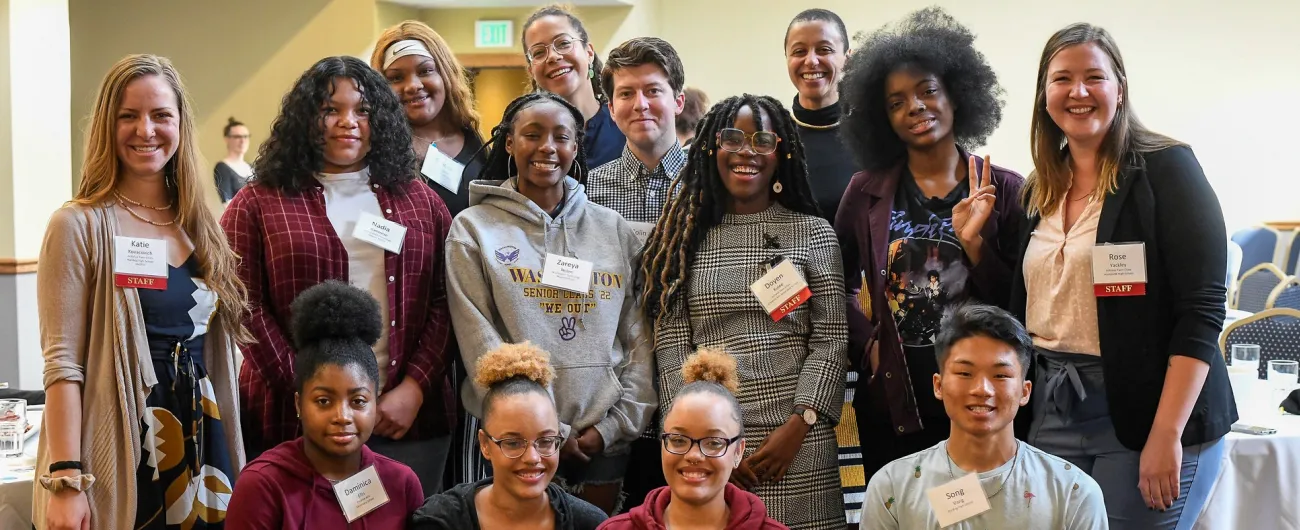 Eight students and six adults at breakfast event smiling at camera