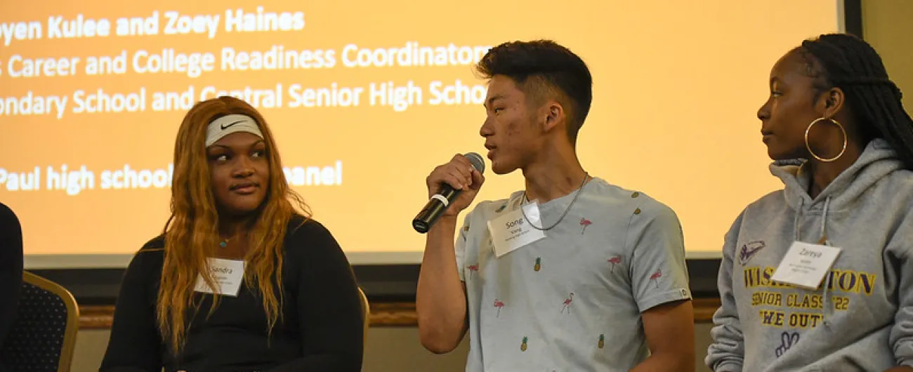 High school student with a microphone sitting by two other students