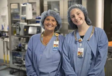 Supervisor and intern in medical scrubs smiling at the camera.